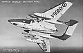 Photo noir et blanc. Avion à aile en flèche et structure bipoutre, vu du dessous. Missiles et réservoirs largables sous les ailes