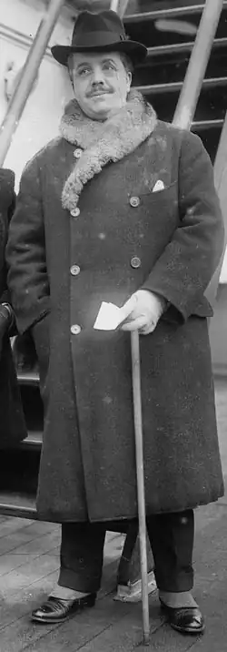 Photographie d'un homme élégant, debout.