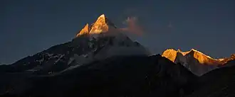 Vue du Shivling (à gauche) et du pic Meru (à droite, en arrière-plan, avec ses trois cimes) à l'aube.