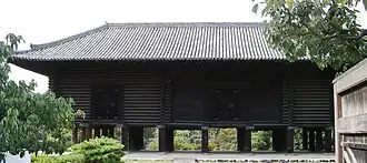 Bâtiment austère en poutres horizontales de bois nu.