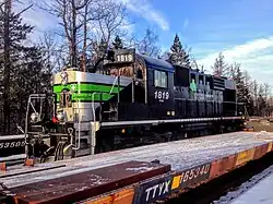 Une locomotive principalement noire, avec des bandes grises et vertes et un logo en forme de feuille portant l'inscription «&nbsp;1819&nbsp;» et&nbsp;« société du chemin de fer de la Gaspésie&nbsp;».