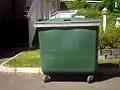 Poubelle d'extérieur en matière plastique sur roulettes pour usage collectif.