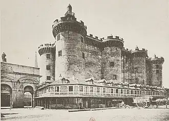 Photographie noir et blanc d'un batiment en pierre, avec plusieurs tours circulaires.