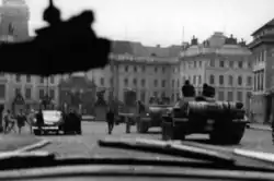 Photo noir et blanc montrant plusieurs chars passant à côté de voitures civiles