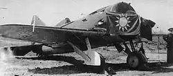 Photo en noir et blanc d'un avion portant sur son hélice un drapeau représentant un soleil.