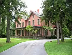 Photographie d'une grande maison de briques entourée par des arbres