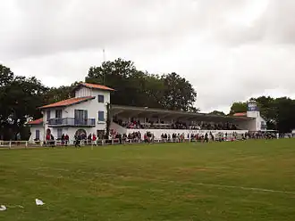 Après un match, une tribune en béton accolée à des bâtiments de style architectural basque et landais.