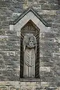 La statue de saint Denis dans une niche du clocher.