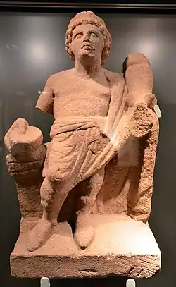 Statue en grès jaune-rouge d'un génie tenant une double corne d'abondance.