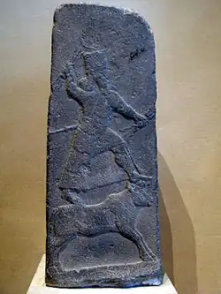 Adad sur son animal-symbole, le taureau, tenant des foudres dans ses mains, stèle d'Arslan Tash, VIIIe siècle av. J.-C., musée du Louvre.