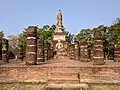 Grand wihan aux escaliers et sol en briques, aux colonnes en latérite avec en arrière-plan le chedi principal du temple sur un axe est-ouest.