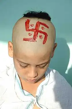 Outre le svastika de l'initiation brahmanique, cet enfant porte le shikha, ou choti, touffe de cheveux en haut du crâne, que tout hindou peut porter en tant que symbole sacré.