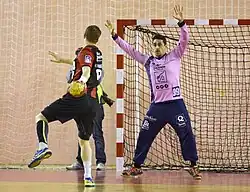 Photo d'un gardien de handball subissant un tir.