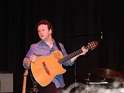 Homme sur scène avec une guitare acoustique.