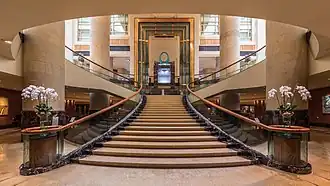 Vue symétrique de l'escalier de l'hôtel The Fullerton, Singapour, avec des rampes décorées de bouquets de fleurs. Juin 2018.