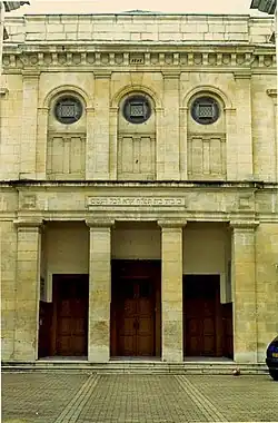 Vue d’un bâtiment de style néoclassique, de pierre jaune.