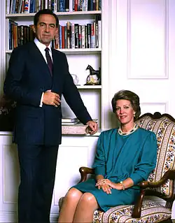 Portrait d'un homme (debout) et d'une femme (assise) devant une bibliothèque.