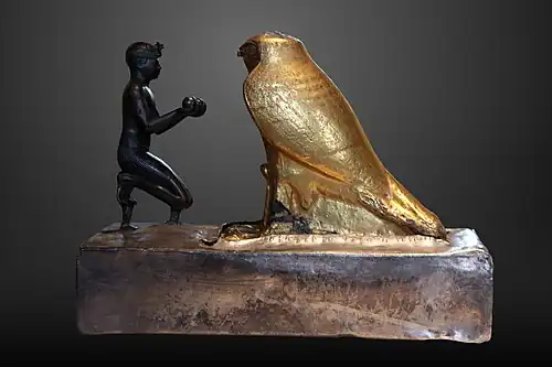 Taharqa offre des vases de vin à Hemen. Bronze (roi), grauwacke plaquée d'or (Hemen), socle en bois plaqué d'argent, H. 19,70 cm. XXVe dyn.Louvre