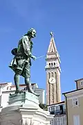 Le monument à Tartini et en arrière-plan le campanile de l'église Saint-Georges&nbsp;(sl).
