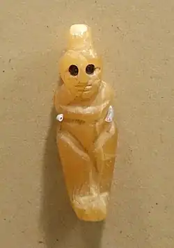 Petite statuette féminine stylisée taillée dans une pierre translucide. Les yeux sont noirs.
