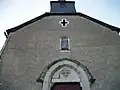 La façade de l'église avec une statue de la Vierge à l'Enfant protégée dans un coffret et une vitre.