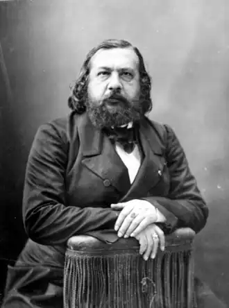 Portrait photographique d'un homme assis sur une chaise retournée.