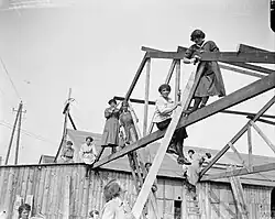Le 26 juin 1918 près de Calais, un groupe de femmes employées comme charpentier assemblent une construction préfabriquée britannique, à usage militaire, produite par l'entreprise de Walter George Tarrant. (Durant le Premier conflit mondial, beaucoup de femmes participent à l'effort de guerre, en remplaçant les hommes partis combattre au front pour de multiples tâches jusqu'alors pourtant considérées comme masculines).