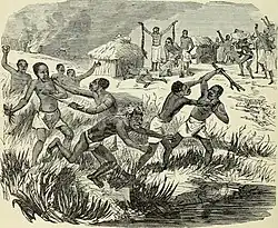 Plusieurs groupes de personnes noires se battent dans les hautes herbes avec des armes. Dans l'arrière plan de l'image se trouve un village avec des activités festives et ce qui ressemble à un homme pratiquant à un rituel.