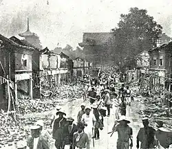 Photo noir et blanc de passants dans une ville en ruine.