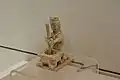 Figurine en terre cuite. Potier en train de pilonner des matériaux pour la céramique, dans un mortier.