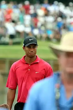 Dans une image flou, un homme au polo rouge et à la casquette noire est mise en avant par sa netteté.
