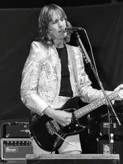Photo en noir et blanc d'un homme en train de chanter et de jouer de la guitare