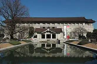 Photo d'un bâtiment longiligne, avec au premier plan, un bassin rectiligne meant à l'entrée du bâtiment.