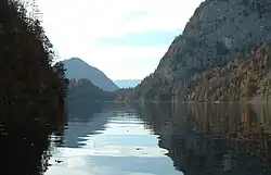Un lac entouré de collines boisées et de montagnes.