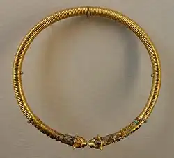 Torque en or incrusté de nacre, lapis-lazuli et turquoise, dont les extrémités sont en forme de têtes de lion.