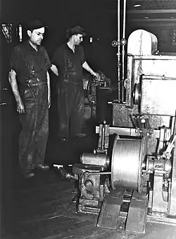 Deux travailleurs qui regarde les réglages d'une machine à droite de ceux-ci.
