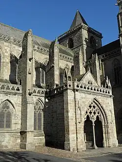 Photographie d'un porche monumental appuyé sur une nef d'église.