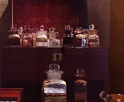 Coffret en bois, couvercle relevé, dans lequel sont rangés des flacons en verre.