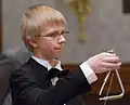 Un jeune musicien d'orchestre jouant du triangle.