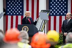 Donald Trump brandit devant un public une grande pancarte figurant les tarifs douaniers supplémentaires.