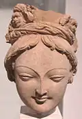 Tête de bodhisattva à la tiare ornée de grotesques. Tumshuq, Toqquz-Saraï, IVe – Ve&nbsp;siècle. H. 16&nbsp;cm. Musée Guimet