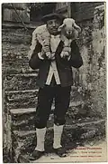 Photographie en noir et blanc d'un homme portant un agneau sur ses épaules.