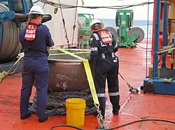 photo de 2 inspectrices examinant un objet sur le pont d'un bateau