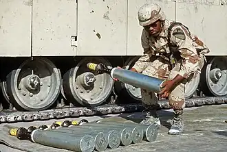 Un militaire américain manipulant un obus-flèche en uranium appauvri M833 de 105&nbsp;mm durant l'opération Bouclier du désert. La pointe du M833 est recouverte d'un embout protecteur en polystyrène.
