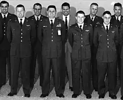 Neuf hommes en tenue militaire, souriants, face à la caméra.