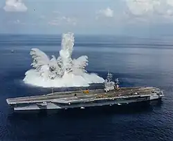 Photographie des gerbes d'eau projetées en l'air par l'explosion d'une bombe sous-marine, à proximité du navire.