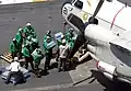 Des marins américains déchargeant des packs de bouteilles d'eau d'un C-2 Greyhound.