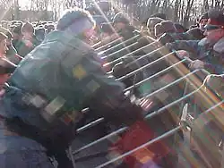 Photographie de policiers appuyés contre des grilles pour empêcher des manifestants de les renverser.