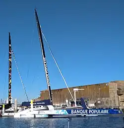Vu de trois quarts avant, un trimaran géant amarré au ponton.