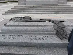 Une tombe en granite gravée Tom du Soldat inconnu sur le côté; une sculpture à relief en bronze se trouve au sommet du sarcophage